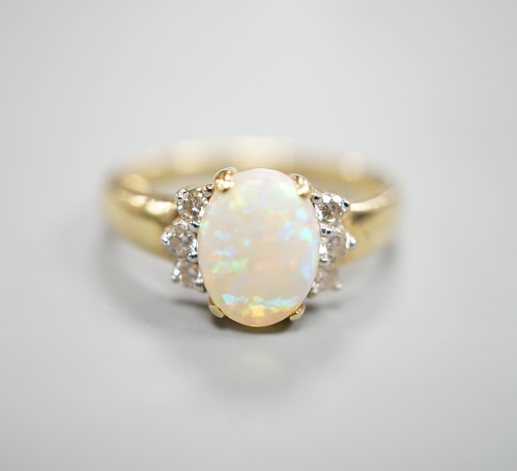 A modern 14k yellow metal, oval white opal and six stone diamond set cluster ring, size N, gross weight 2.9 grams.